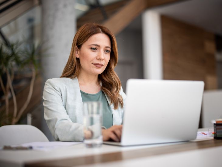 Erfolgreiche Geschäftsfrau mit Laptop, arbeitet im Büro.